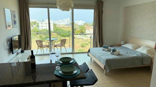 Un dormitorio con una cama y una mesa con platos. en Too Coool Studio Apartment Coralli Resort, en Protaras