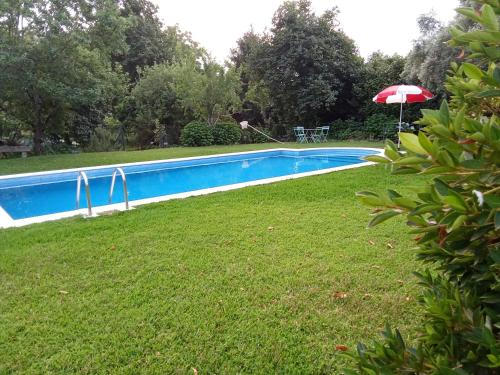 a swimming pool in a yard with an umbrella at Quinta da Maínha - Charming Houses - Escape to Nature in Braga