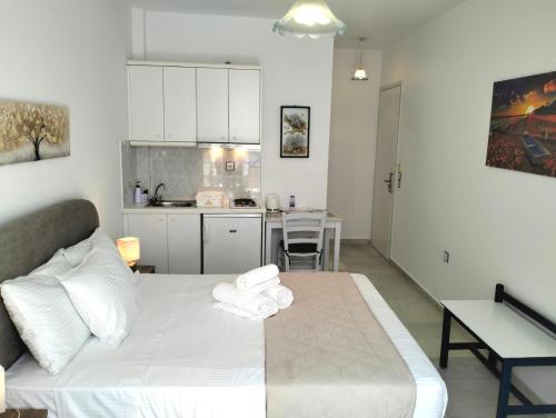 a bedroom with a white bed and a kitchen at Nostos Studios at Saint George beach Agios Georgios Chora Naxos town in Naxos Chora