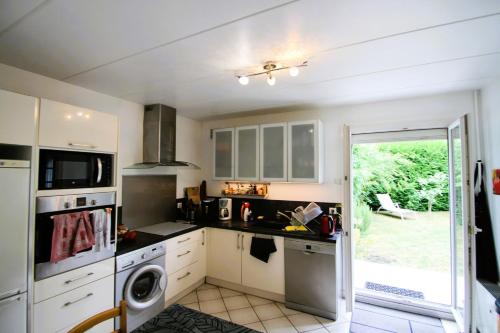 une cuisine avec des armoires blanches et une laveuse et une sécheuse dans l'établissement Le Jardin Champenois Maison, à Tinqueux