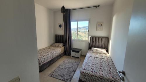 a small bedroom with two beds and a window at Appartement Élégant avec vue plage et montagne d'arganier Family Only in Imi Ouaddar