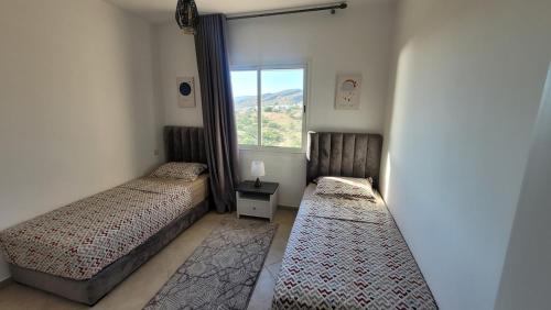 a bedroom with two beds and a window at Appartement Élégant avec vue plage et montagne d'arganier Family Only in Imi Ouaddar