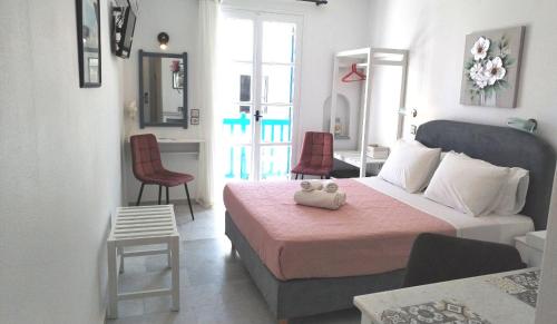 a bedroom with a bed with pink sheets and red chairs at Nostos Studios at Saint George beach Agios Georgios Chora Naxos town in Naxos Chora