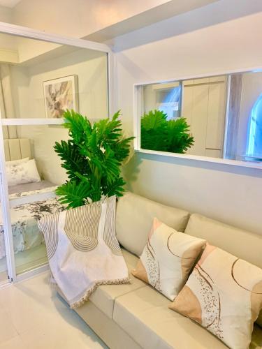 a living room with a couch with pillows and a plant at Primeworld District Condoresort 15mins2airport in Mactan Island