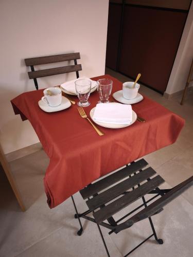 a table with a red table cloth and plates and glasses at Chambre chez l'habitant à Pernes les Fontaines in Pernes-les-Fontaines