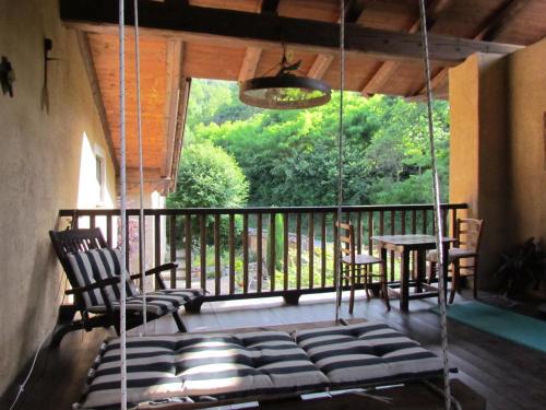 a porch with a swing and a table and chairs at Alloggio Albaluna in Dronero