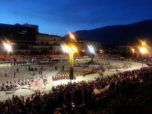 a crowd of people watching a performance in a square at night at Piazza Maggiore in Sulmona