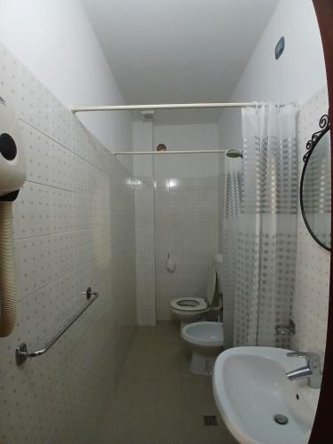 a white bathroom with a toilet and a sink at Albergo Ristorante Gualtieri in Barberino di Mugello