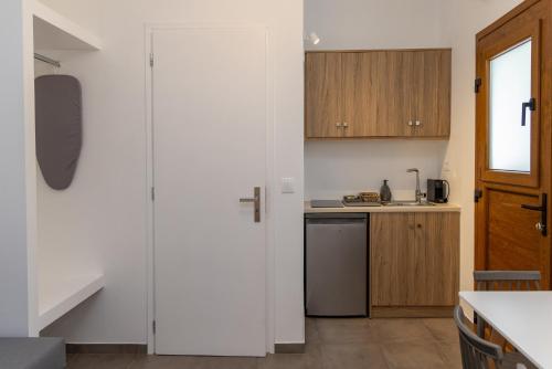 a kitchen with white walls and wooden cabinets at Green Dream in Tinos Town