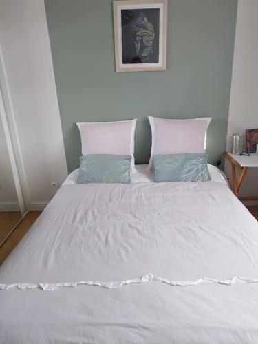 a bed with white sheets and blue pillows at Chambre Zen à la campagne in Marennes