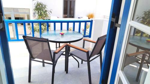 a glass table and two chairs on a balcony at Nostos Studios at Saint George beach Agios Georgios Chora Naxos town in Naxos Chora