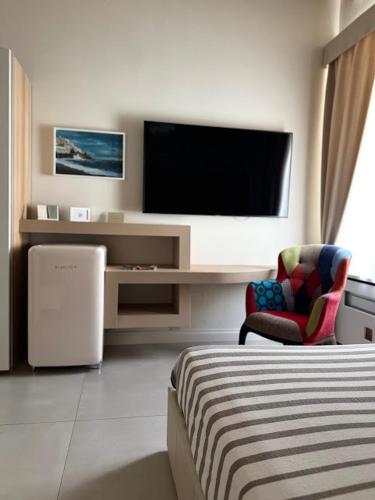 a hotel room with a tv and a bed and a chair at Le Suite del Duomo in Cava deʼ Tirreni