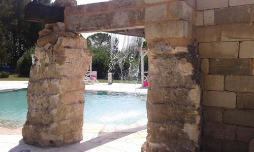 a stone archway next to a swimming pool at Le Pentume in Arnesano