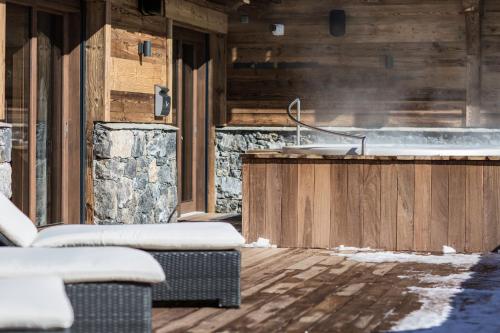 un jacuzzi dans une maison en bois avec de la neige dans l'établissement Chalet Le Saint-Jean - 15 pers - proche pistes, aux Gets