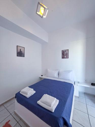 a white bedroom with a blue bed with towels on it at Calypso Heaven in Santorini