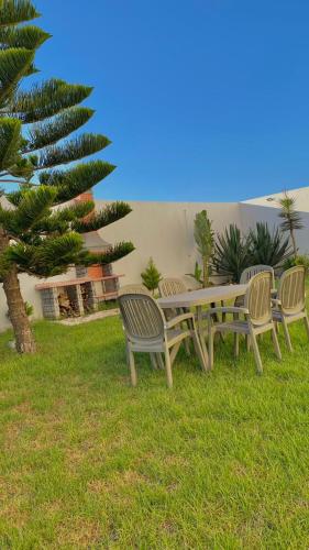 a picnic table and chairs in the grass with a palm tree at Luxus Apartments in Kelibia