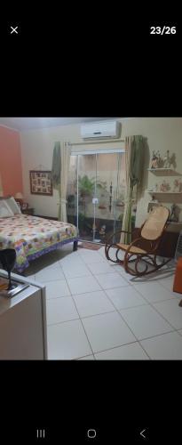 a bedroom with a bed and a chair and a window at Casa JB in Chapada dos Guimarães