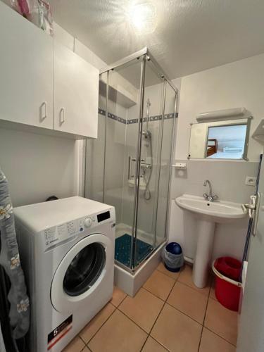 une salle de bain avec une machine à laver et un lavabo dans l'établissement Belle villa entièrement climatisée 4 chambres 10 couchages, fibre WIFI, 2 terrasses parking privatif dans résidence sécurisée piscine commune 800 m de la mer LRCS69, à Portiragnes