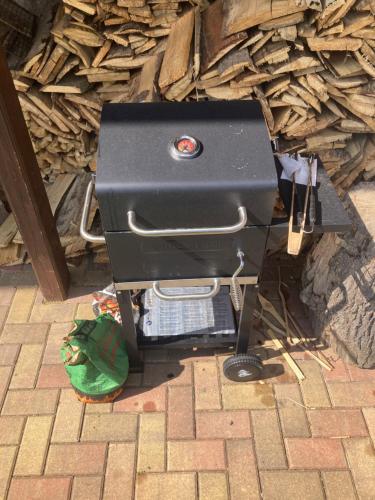 a grill sitting on the ground next to a pile of wood at Apartmán u Bětky in Jablonec nad Jizerou