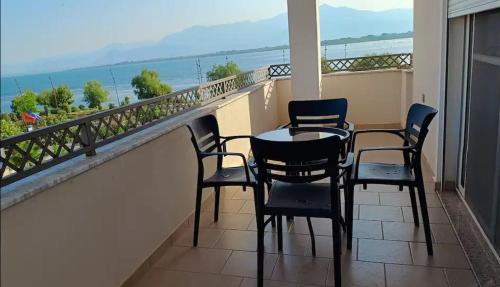 a balcony with four chairs and a table and a view of the ocean at Lake Retreat Villa in Shkodër