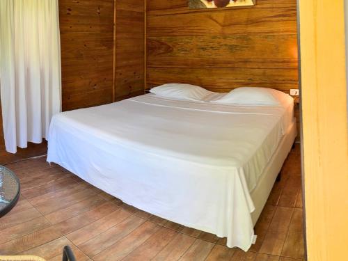 a bedroom with a white bed with a wooden wall at Tombo Beach in Guarujá