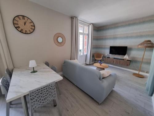 un salon avec un canapé et une horloge au mur dans l'établissement Le Cosy, à Mers-les-Bains