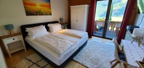 a bedroom with a bed and a large window at Urlaub am Krausberghof, Apartment mit Balkon und Parkplatz, Aufenthaltsraum, Sauna und Infrarotkabine, inmitten der Natur, kostenfreie Kaffeekapseln, 6 Fahrminuten zur Alpentherme Gastein und zur Schlossalmbahn, Spielplatz, großer Gartenbereich in Bad Hofgastein