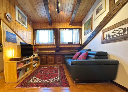 a living room with a couch and a television at Mansarda Chiara - locazione turistica in Gosaldo