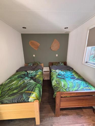 two twin beds in a room with a window at Mooi chalet op de Veluwe! in Lunteren