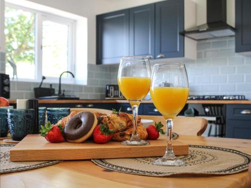 two glasses of orange juice and strawberries on a wooden table at No 2 Badger Sett-Uk44307 in Lenwade