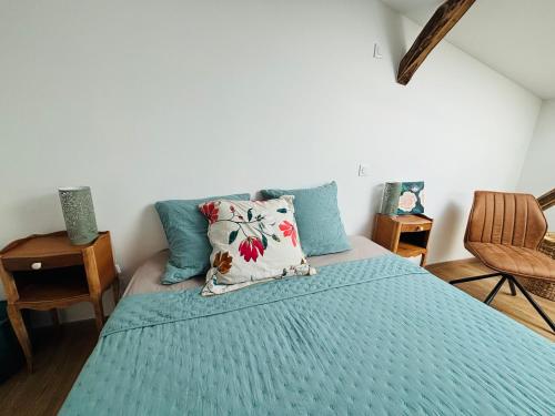 a bedroom with a bed with a blue comforter at L'Atelier des Rêves Les Gîtes de l'Atelier in Gaudonville