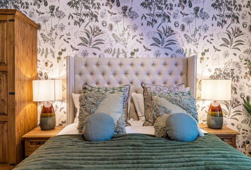a bedroom with a bed with blue pillows and wallpaper at the Herbalist in Tihany