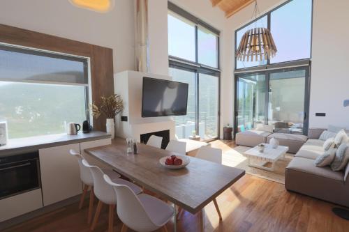 a living room with a table and chairs and a tv at The Dynasty Villas in Sivota