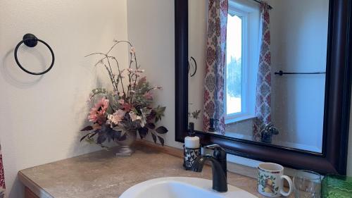 a bathroom sink with a vase of flowers next to a mirror at Majestic View Roundhouse - Relax Room in Wasilla