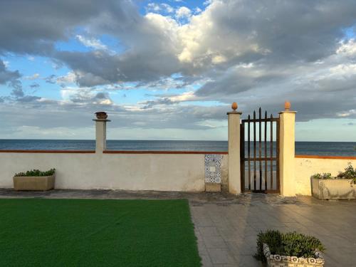 a fence with a green lawn in front of the ocean at Terrazza delle Acacie in Villaggio San Leonardo