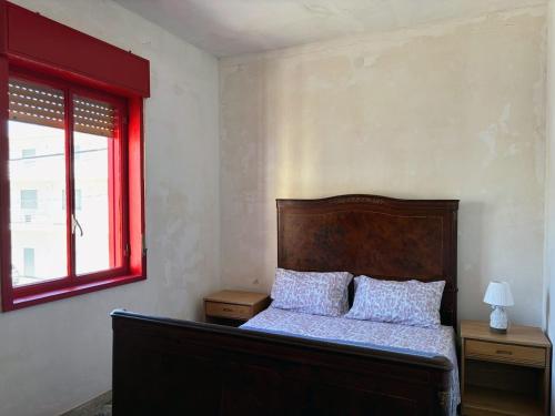 a bedroom with a bed with a red window at Terrazza delle Acacie in Villaggio San Leonardo
