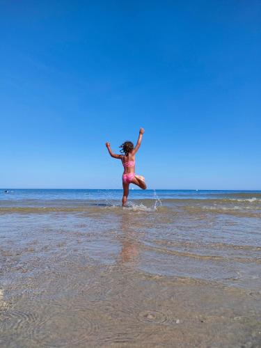 a woman jumping in the water on the beach at Sunset Spot à Bredene in Bredene