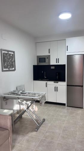 a kitchen with a table and a stainless steel refrigerator at Brisa Marina Apartamento con vistas al mar in Mazagón