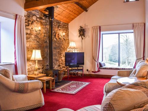 a living room with a couch and a tv at Spring Grove in Pooley Bridge