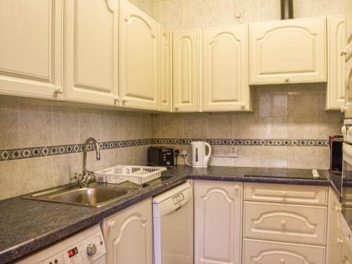 a kitchen with white cabinets and a sink at Spring Grove in Pooley Bridge
