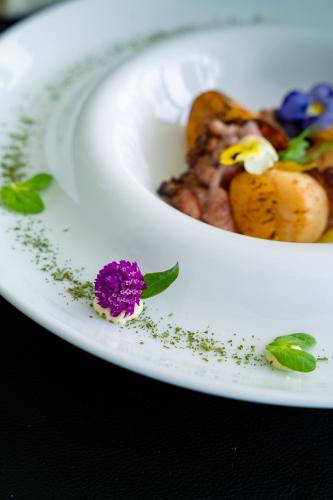 a plate of food with a purple flower on it at Porto Covo Praia Hotel & SPA in Porto Covo