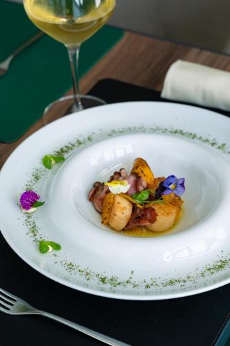 a plate of food on a table with a glass of wine at Porto Covo Praia Hotel & SPA in Porto Covo