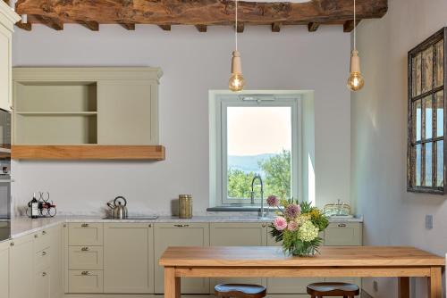 a kitchen with a wooden table with a vase of flowers on it at Castello Vicchiomaggio in Greve in Chianti