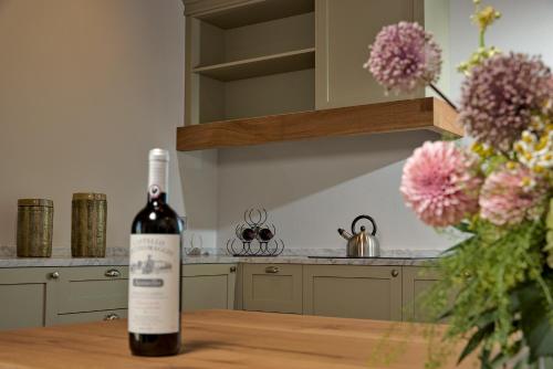 a bottle of wine sitting on a table with a vase of flowers at Castello Vicchiomaggio in Greve in Chianti