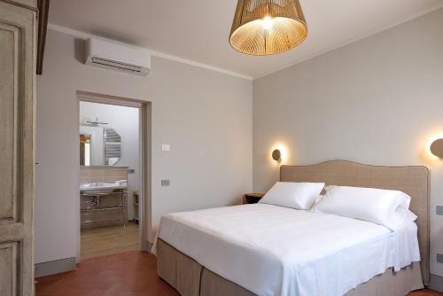 a bedroom with a white bed and a mirror at Castello Vicchiomaggio in Greve in Chianti
