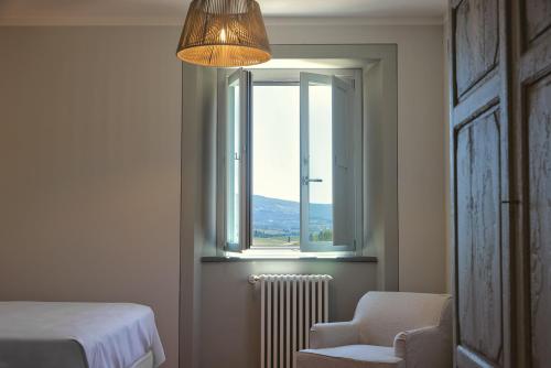 a bedroom with a bed and a window and a chair at Castello Vicchiomaggio in Greve in Chianti