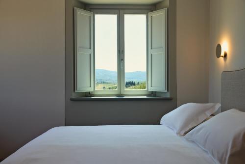 a bedroom with two white beds and a window at Castello Vicchiomaggio in Greve in Chianti