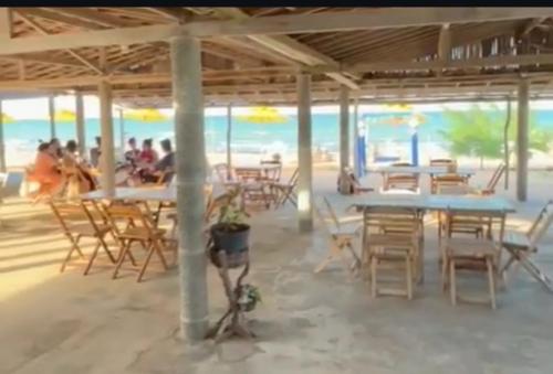 un restaurant sur la plage avec tables et chaises dans l'établissement Pousada Quinta das Flores, à Icapuí