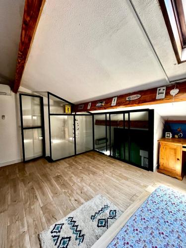 un salon vide avec des portes vitrées et du parquet dans l'établissement Maguelone Centre - 4 pers, wifi, Clim, à Villeneuve-lès-Maguelone