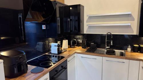 a kitchen with white cabinets and a stove top oven at Ultra-Central Loft Penthouse Sky Sports & Movies in Leeds